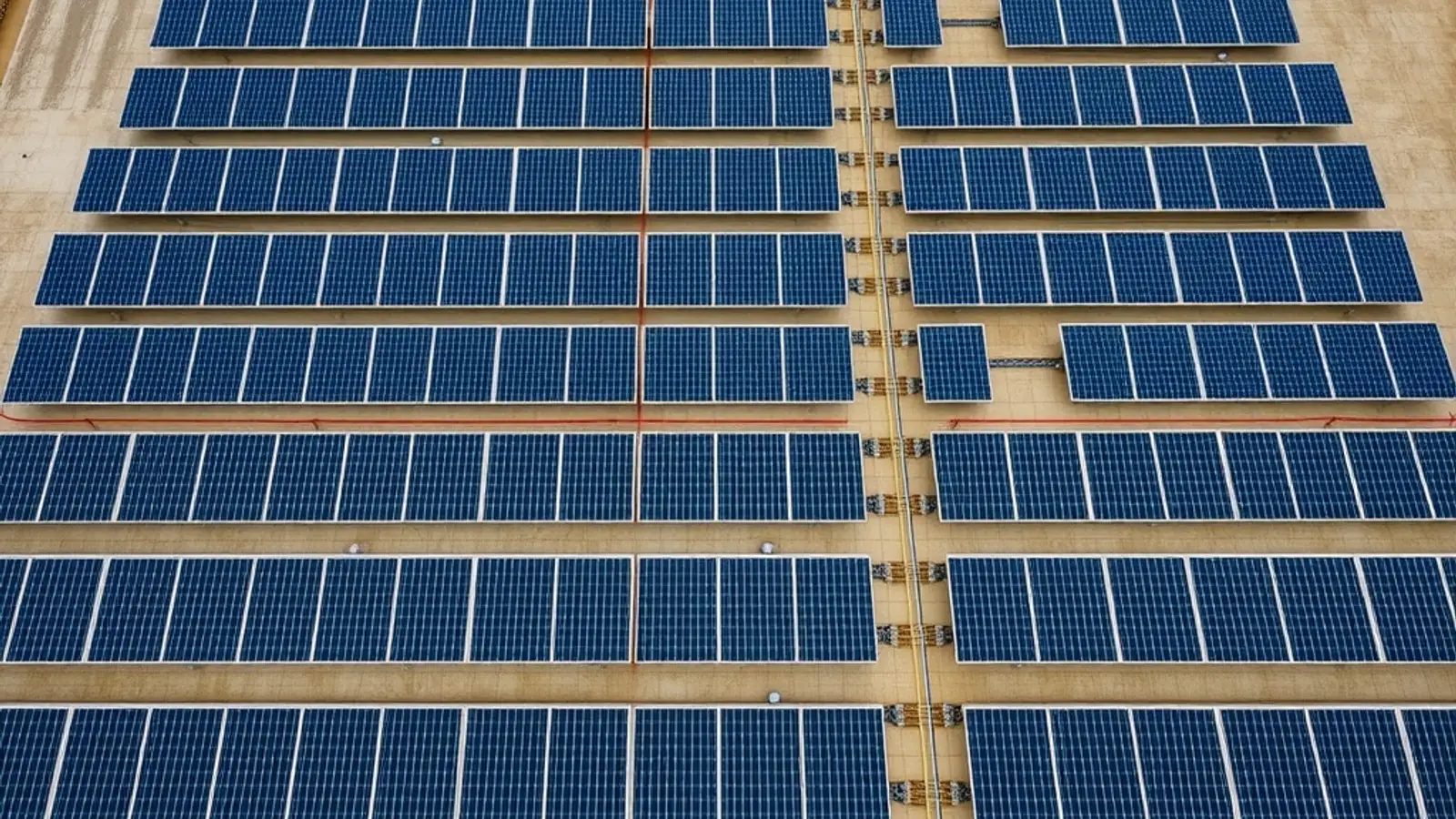 Top-down view of a neatly laid out flat-roof solar array with cable trays and walkways